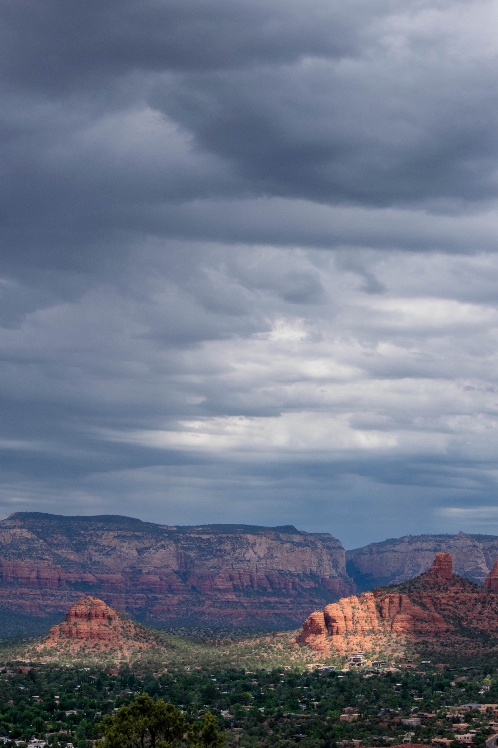 Dark storm clouds over red rock buttes and the town of Sedona
